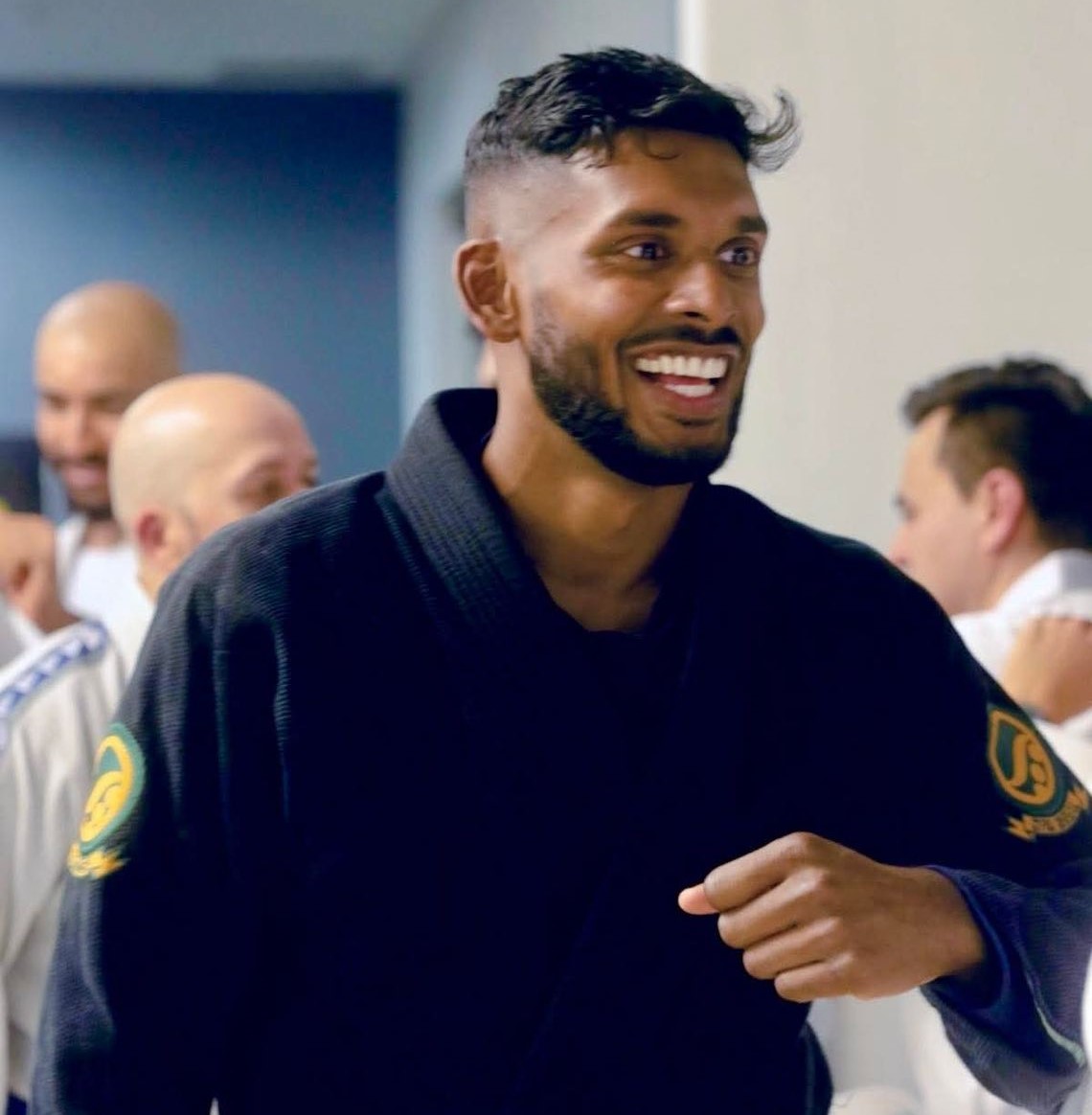 Martial artist in black gi smiling during training session.