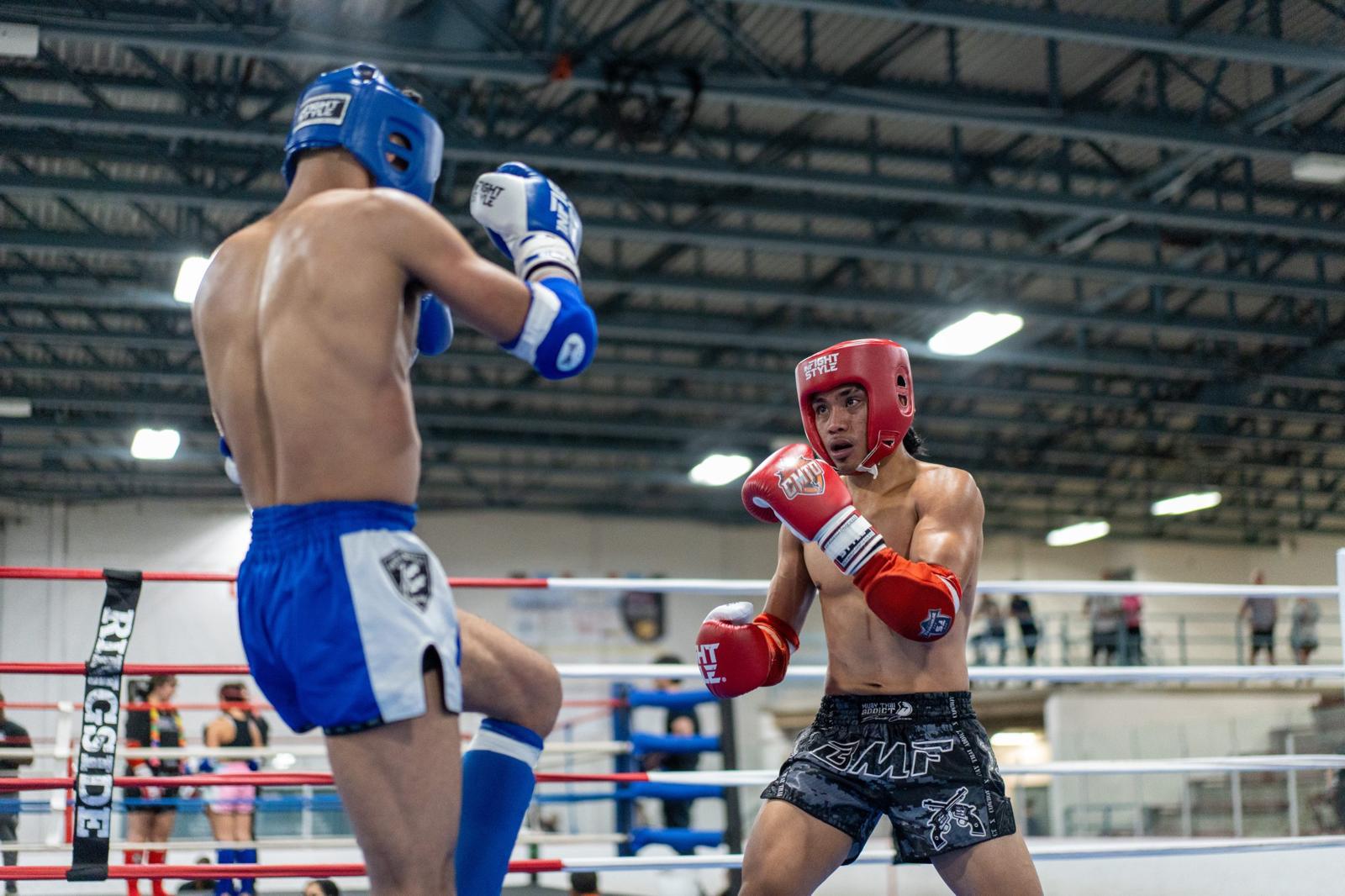Boxers sparring in the ring with protective gear and focused expressions at a gym.