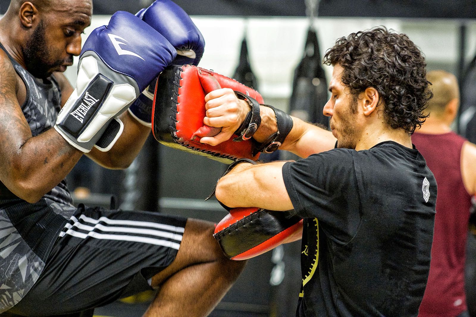 beginner-friendly-muai-thai-classes-toronto-revmma Student throwing a knee strike on focus mitts during a beginner Muay Thai class at REVMMA Toronto
