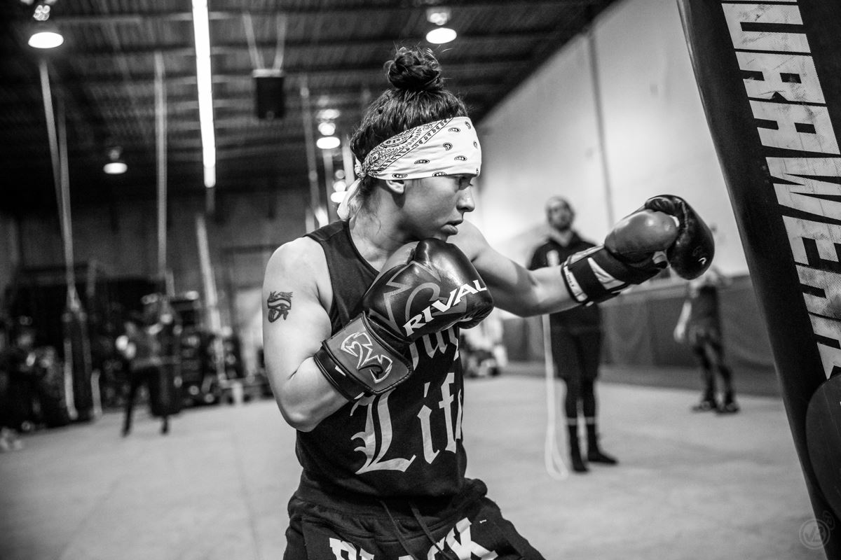 Female boxer training with a punching bag in a gym, showcasing focus and determination.