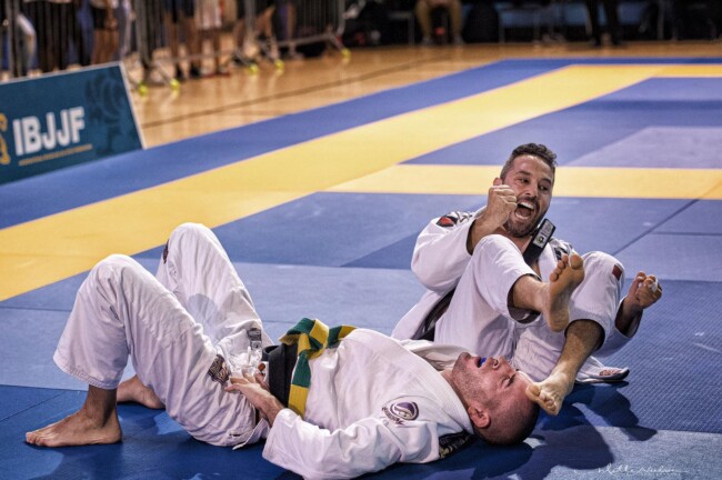 Joel winning via arm bar submission, Toronto Open. Two Brazilian Jiu-Jitsu competitors on the mat, one celebrating victory, the other lying down at IBJJF event.