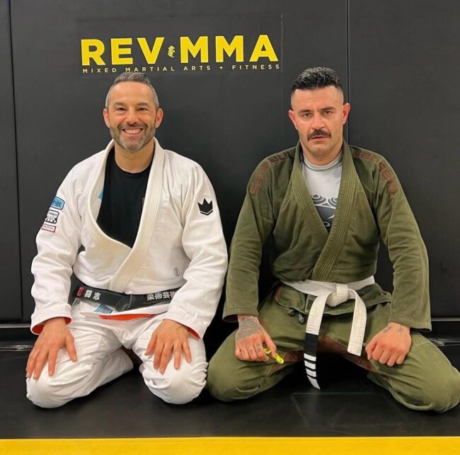 Joel training Persian singing sensation and activist Shahin Najafi at RevMMA. Two men in martial arts gis sitting on the mat at Rev MMA gym.