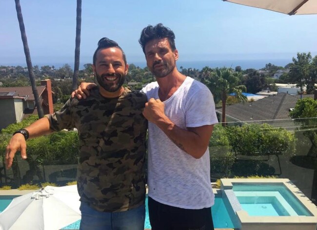 Joel with action star Frank Grillo at his house in Hollywood. Two men smiling outdoors with a scenic view of palm trees and the ocean in the background.