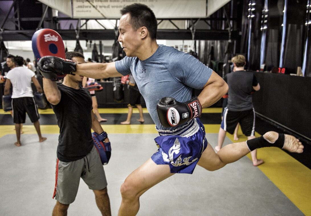 Man throwing a knee strike on Thai pads during a Toronto kickboxing class at REVMMA
