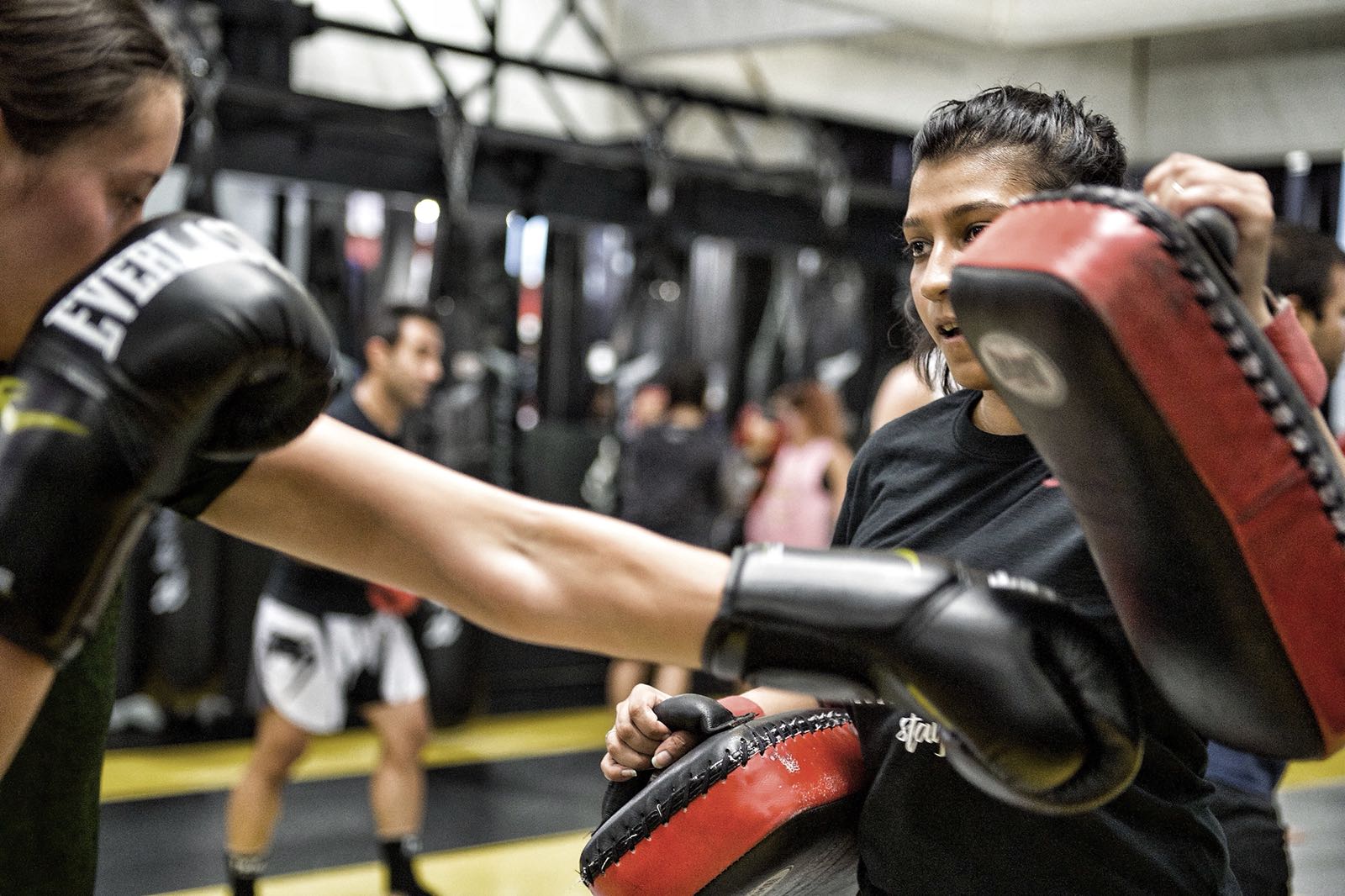 Two members working pad drills together in a Toronto kickboxing class at REVMMA