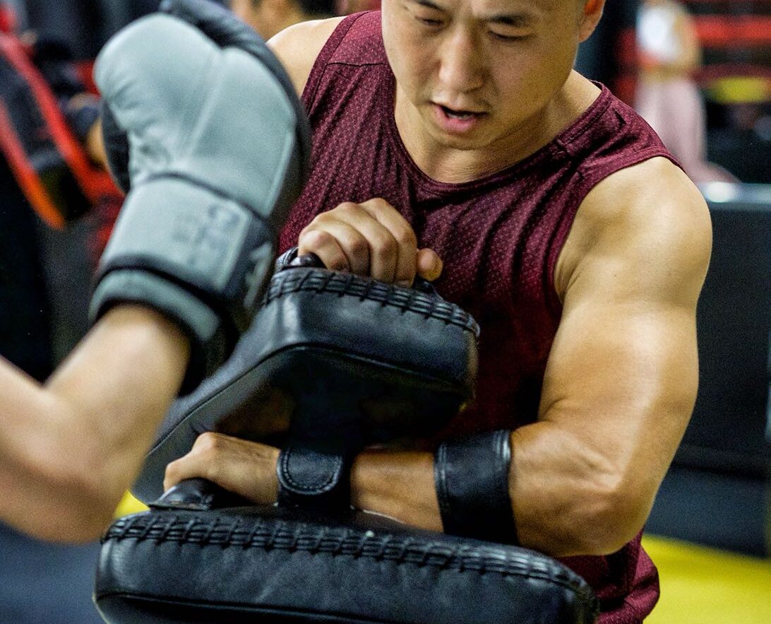 muay-thai-toronto-classes-revmma Student holding Thai pads during a Muay Thai training session at REVMMA gym in Toronto
